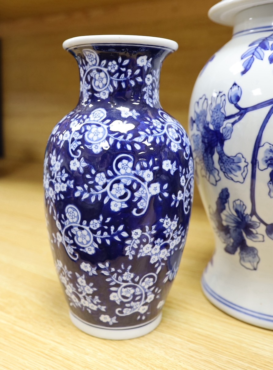 A pair of Japanese black ground vases, a pair of Chinese blue and white vases and covers, a similar pair of jars and a vase, four wood stands. Largest 41cm